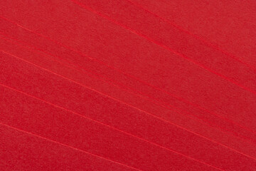 Fototapeta premium Close-up of Vibrant Red Paper Texture with Layered Edges,A high-resolution close-up shot of stacked red craft paper, showcasing a rich fibrous texture and subtle diagonal lines from the paper edges.