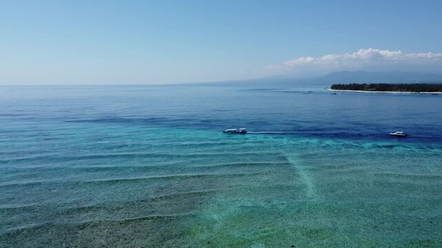 Aerial drone ascending and tilting down revealing ocean depth gradient near Gili Trawangan, Indonesia.