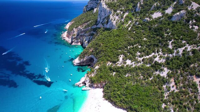 Cala Sisine Sardinia 4k drone video of tour boat and majestic cliff on beach. Scenic Orosei gulf view of turquoise sea and huge limestone rocks in Italy. Mediterranean nature drone follow scenery