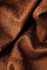 Fototapeta premium Soft brown fabric showing folds and texture under natural light in a simple indoor setting during daytime