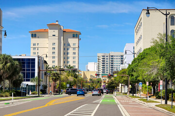 Obraz premium Bike lane in bright green in Sarasota city, Florida. Cars traveling nearby on public road. Urban mobility solutions