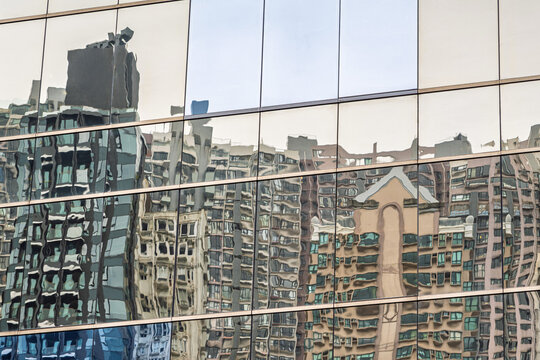 Abstract urban reflections on glass facade with distorted city buildings creating geometric patterns and modern architectural texture