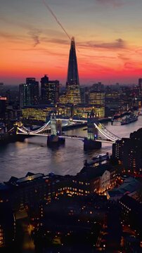Aerial sunset view towards the Tower Bridge in London, England, with city skyline and river Thames