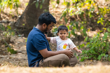 Fototapeta premium The man is engaging playfully with the baby in an outdoor environment