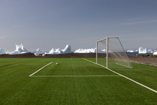 Soccer goal on green field with icebergs in the background on Disko Island in Greenland