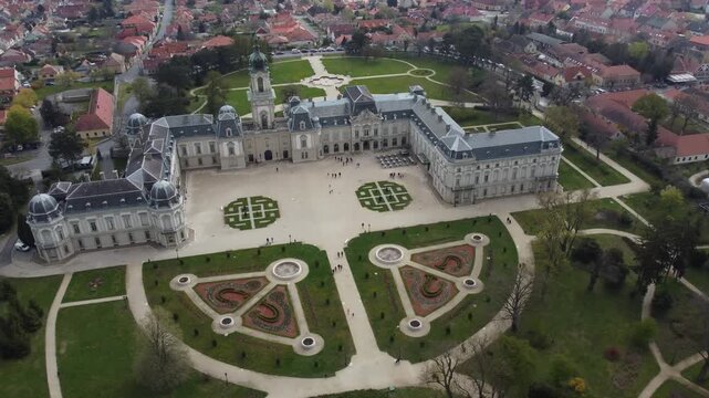 Aerial drone view grandeur of Festetics Palace in Keszthely, Hungary, surrounded by meticulously designed gardens and pathways. The baroque architecture, with its ornate facade.
