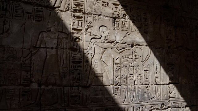 Karnak Temple in Luxor, Egypt. Dramatic sunlight beam on ancient Egyptian wall relief with pharaoh figure and hieroglyphics at Karnak Temple Luxor.