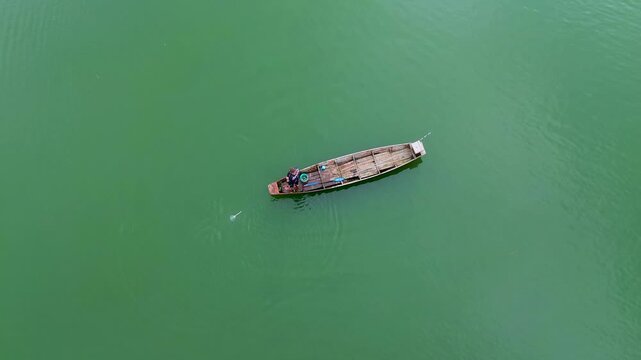 4K Aerial Drone View of Traditional Fisherman Casting Net from Wooden Boat on Lake in Malang Indonesia