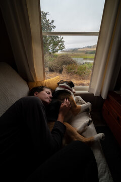 A woman relaxing on a couch with a dog