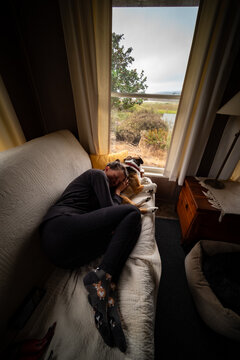 A woman relaxing on a couch with a dog