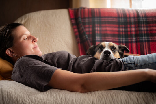 A woman relaxing on a couch with a dog