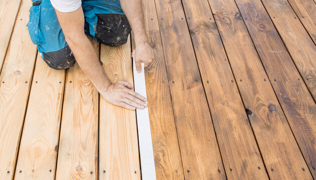 Worker kneels on wooden deck