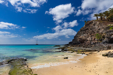 Naklejka premium Panoramic view of a sandy beach with turquoise ocean under a blue sky, Morro Jable, Canary Island, Fuerteventura, background or wallpaper for your project 