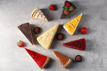 Pieces of different tasty cakes and candies on grey table, flat lay