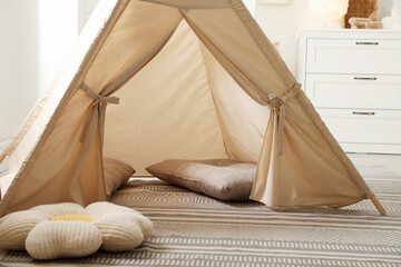 Stylish toy wigwam and pillows on floor in playroom. Interior design © New Africa