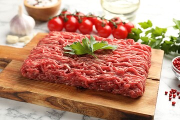 Fototapeta premium Raw minced beef, parsley, tomatoes and spices on white marble table, closeup