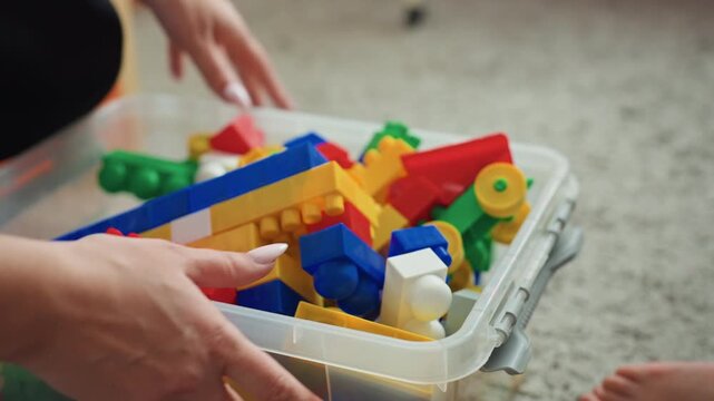 Parent and child building together. Mother and her son engaging in constructive play with blocks. Loving mother and young boy assembling colorful bricks on floor with gentle instruction
