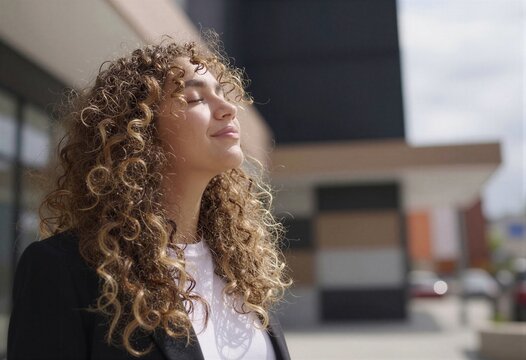 Una joven con cabello rizado disfruta de un momento de paz en un entorno urbano.