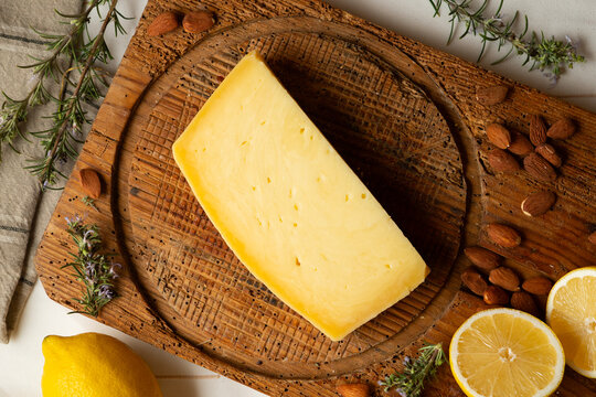 Artisan cheese blocks of Sicilian Ragusano with rosemary sprigs and almonds on a rustic wooden board