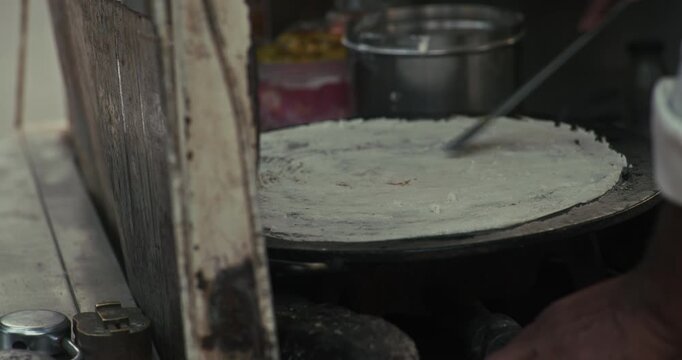 Street style dosa making on an Indian roadside stall, crispy dosa being prepared live with spicy potato chutney filling, authentic South Indian street food experience