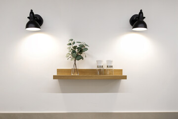 Wooden shelf with decorative items and two wall lamps © Olga Mukashev