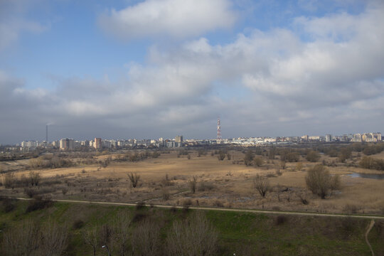 Wide panoramic view of Vacaresti Nature Park wetlands with the Bucharest city skyline under a cloudy sky