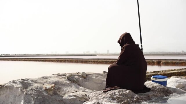 Hooded Jedi person fishing patiently at a pink salt lake