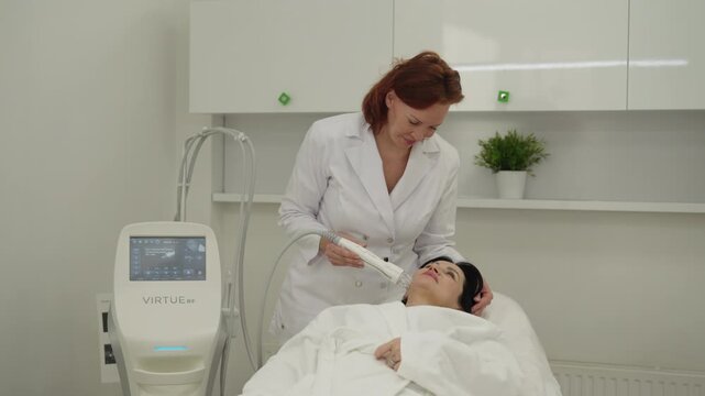 Ufa, Russia - 27 January 2026. Portrait of professional dermatologist performing microneedle radiofrequency face lifting procedure on patient in modern beauty clinic for skin rejuvenation, antiaging.