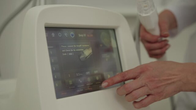 Ufa, Russia - 27 January 2026. Professional esthetician setting up modern fractional radiofrequency microneedling device, adjusting parameters on digital screen before facial rejuvenation therapy.
