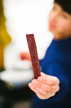 A young man offers up a stick of beef jerky while backpacking in winter