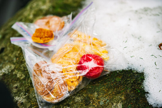 A squished bagel, crackers, and a small apple in a plastic bag during a winter backpacking trip