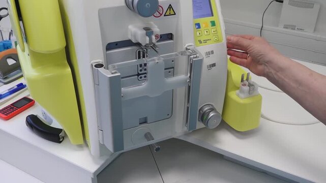 Blood donation machine setup process with visible components, buttons, and accessories in a clinical environment