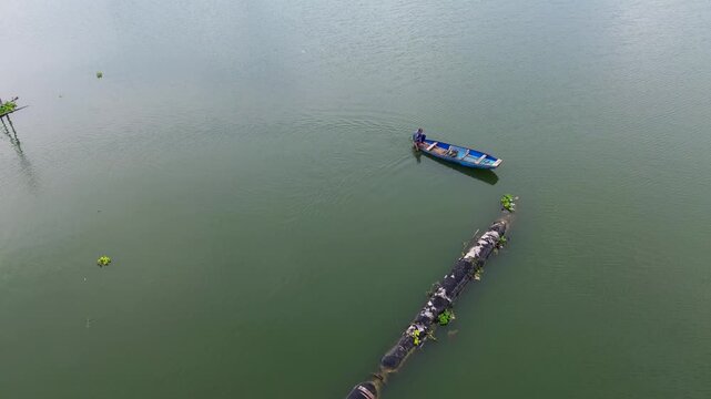 4K Aerial Drone View of Traditional Fisherman Casting Net from Wooden Boat on Lake in Malang Indonesia