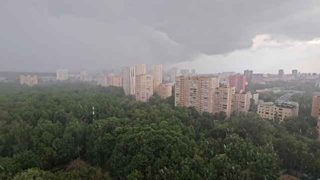 City skyline with a large rain cloud in the sky. The city is surrounded by trees and buildings