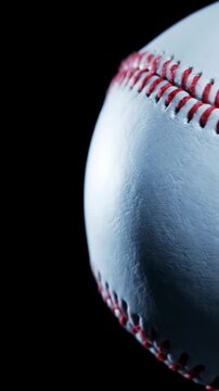 Close-up of a classic baseball with red stitching against a dark black background perfect for sports marketing and athletic social media content. Vertical. Video. Portrait Orientation.