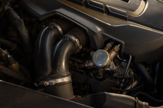 Closeup of fuel system component with hoses and connectors inside car engine bay, detailed view of mechanical parts and pipeline connections.