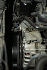 Fototapeta premium Car alternator closeup with belt drive and pulley, visible electrical generator unit mounted on engine in automotive system.