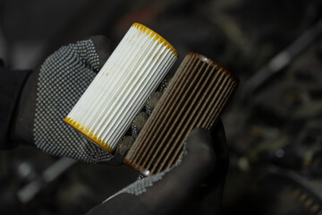 Comparison of new and used car oil filter elements held in gloved hands, clean white cartridge and...