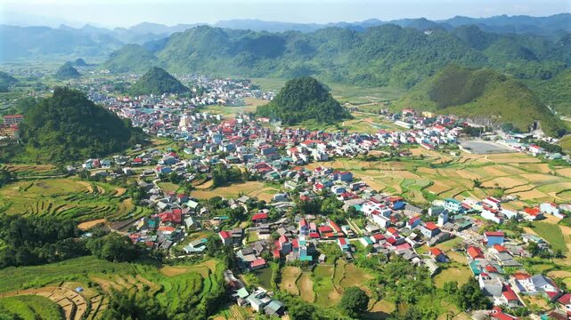 Stunning aerial view of a small town nestled in a beautiful green valley. Rice terraces and karst mountains surrounding the settlement. Tam Son town from a viewpoint