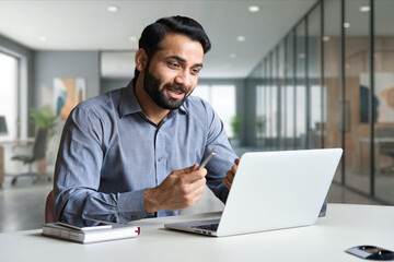 Young bearded indian business man teacher talking, teleworking, having virtual classroom meeting working on laptop computer giving online webinar training, remote class on video conference call.