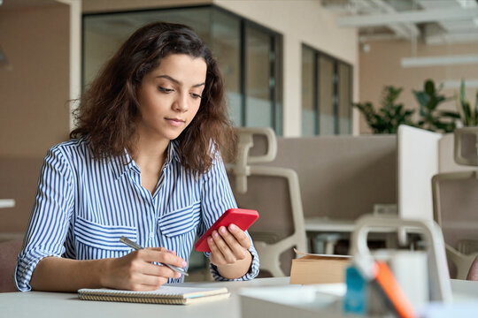 Hispanic latin young teen girl college student holding smartphone studying on cell, distance learning using apps for education, elearning on mobile phone in university campus or creative office.