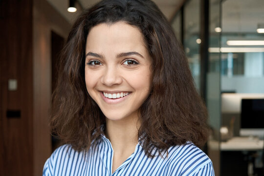 Beautiful happy hispanic ethnic young adult 20s woman looking at camera, headshot. Smiling curly latin girl university student or professional close up face headshot.