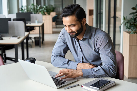 Smiling indian executive manager working at home watching online learning training webinar for employees. Latin Hispanic student having online virtual video call on computer in coworking space.