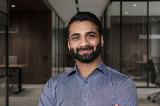 Portrait of young happy indian business man executive looking at camera. Eastern male professional teacher, smiling ethnic bearded entrepreneur or manager posing in office, close up face headshot.