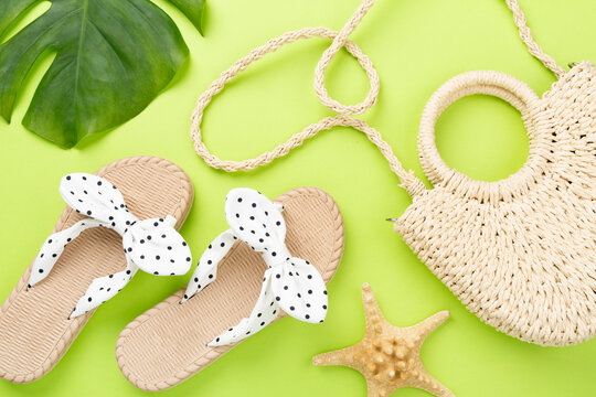 Straw bag with sandals on color background, top view