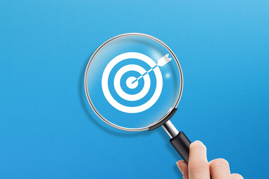 Business target concept with magnifying glass on blue background. 