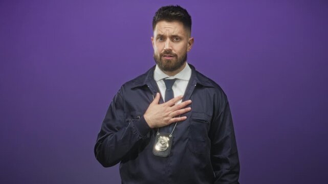 Man detective with police badge and beard placing hand on chest while wearing navy jacket and tie in studio; duty integrity solemn.