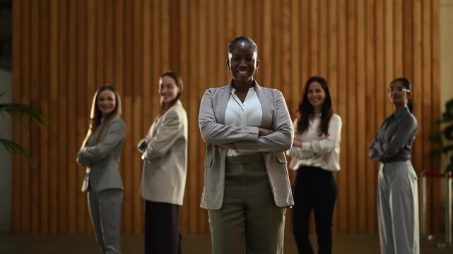 Confident african american business leader walking towards the camera with her multi ethnic female team standing behind
