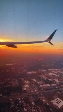 Aerial view from airplane window at sunset over city. Airplane winglet over urban landscape and grid during golden hour in Florida, USA.