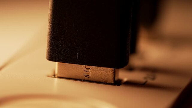 Close-up of a USB cable being plugged into a computer port with warm lighting